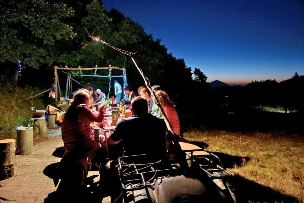 Kamperi večeraju u kampu, dok se  u pozadini vidi planina Rtanj.